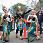 Three young women in traditional Thai Dress pose for the camera near the entrance of the festival.